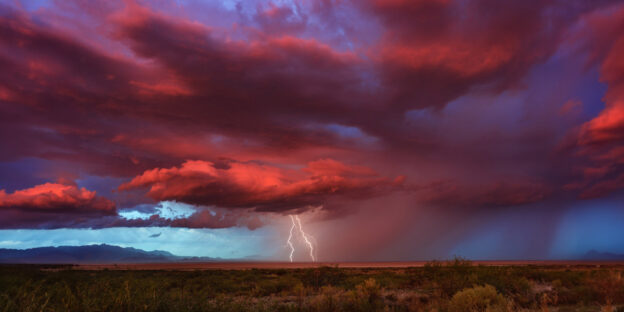 Thunderstorm with lightning bolts striking at sunset.