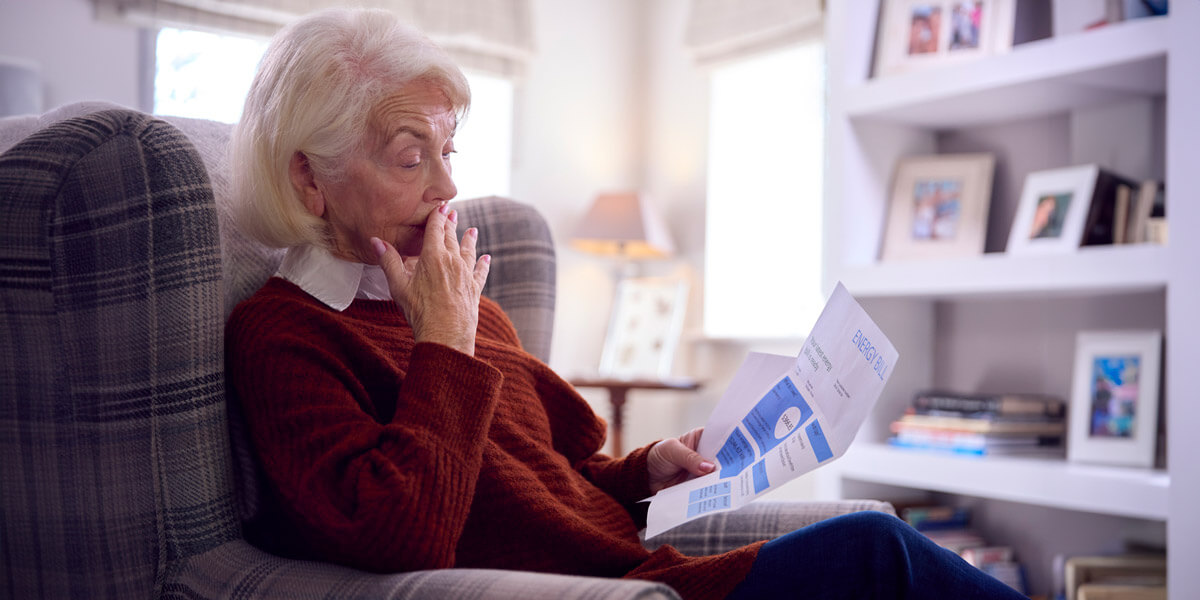An elderly woman engrossed in reading a magazine while comfortably seated in a chair.