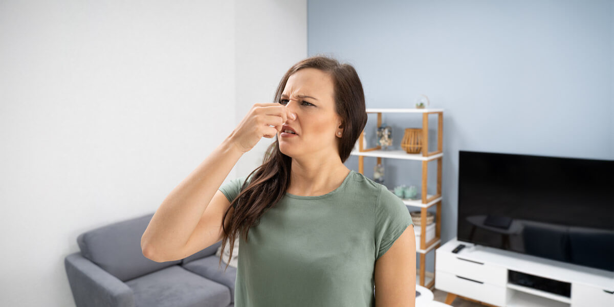 A woman blowing her nose in a living room, possibly due to a cold or allergies.