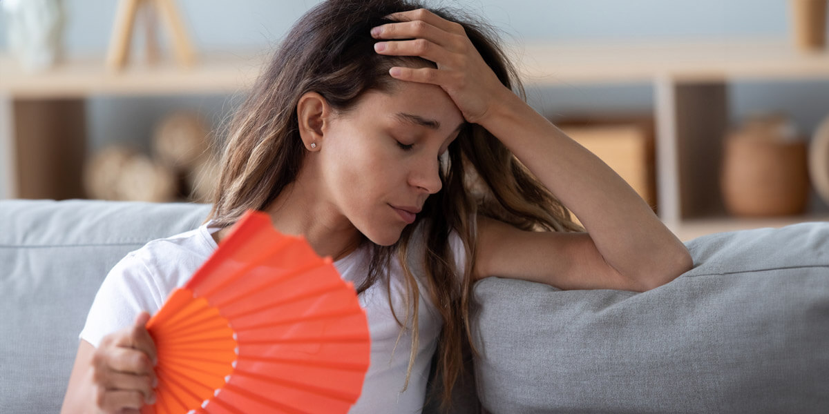 Woman sitting on a couch, holding an orange fan.